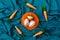 Minimal layout of golden Easter eggs  in orange nest with bunny carrot circling around against cyan or blue background