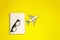 Minimal layout with model airplane, spiral notebook and fashion glasses on yellow background. Directly above. Travel vacation