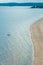 Minimal picture of scenic sand beach coast line of Ladoga lake island in Karelia with two people in kayak in water and pine forest