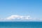 Minimal, serene seascape with blue sky, fluffy white clouds and blue water