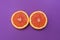 Minimal style, creative layout orange and grapefruit. Flat lay. Food concept. Half an orange on purple background.