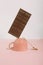 Minimal trendy coffee break concept with cup, chocolate bar and teaspoon on pastel pink background. Modern, romantic aesthetic