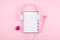 Minimal workplace with white blank notepad, pink headphones, heart, pencil on pink background. Top view. Flat lay