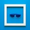 Minimalism. Masterpiece in wooden frame. Sunglasses. Top view. Flat lay. Sun protection concept