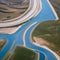 A minimalist aerial view of a winding river, with abstract patterns formed by the meandering flow of water3, Generative AI