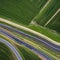 A minimalist aerial view of a winding road, with abstract patterns formed by the arrangement of trees and fields5, Generative AI