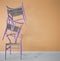 Minimalist architect designer concept with three classic violet wooden chairs hanging in the balance on orange striped wallpaper b