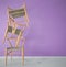 Minimalist architect designer concept with three orange classic wooden chairs hanging in the balance on violet striped wallpaper b