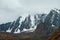 Minimalist atmospheric mountains landscape with big snowy mountain top in low clouds. Awesome minimal scenery with glacier on