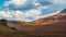 Minimalist autumn landscape with  sunlit orange mountainside on background of mountains silhouettes on horizon. Minimal mountain