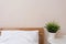 Minimalist bedroom interior design, wooden bed with white linen bedding, bedside table with green plant in pot, empty