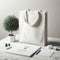 Minimalist chic: elevate your workspace with a white tote bag mockup on a white marble table