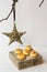 Minimalist Christmas and New Year decoration, rattan star hanging on a dry tree branch, coconut macaroons on a wood box