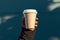 Minimalist coffee moment male hand grips paper cup on blue