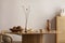 Minimalist composition of dining interior with round wooden table, design chair, vase with dried flowers, coconut in bowl,