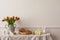 Minimalist composition of living room nterior with copy space, vase with tulips, bread in basket, colorful easter eggs, easter