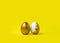 Minimalist Easter composition. Couple of golden painted eggs in row on yellow background.