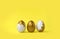 Minimalist Easter composition. Golden decorated eggs in row on yellow background.