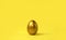 Minimalist Easter composition. Golden egg on yellow background. Trendy color monochromatic concept.