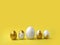 Minimalist Easter composition. Golden paint pouring eggs in row on yellow background.