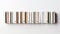 A minimalist and elegant image of a row of books on a white background. The books are of different colors and sizes