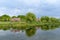 Minimalist garden landscape with willow, plants and grass and pink flowers tree near a lake in a cloudy day in Scotland, United Ki