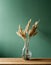Minimalist glass vase of dried grasses on a green background.