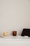 Minimalist home office desk table. Feminine workspace with mug of tea, digital tablet, candle, paper notebooks. White wall
