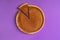 Minimalist image of a pumpkin pie, with one sliced piece and separated, on a purple background. Top view. Traditional dessert.