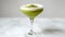 Minimalist Matcha Martini. A pristine matcha martini cocktail graces a sleek martini glass, garnished with a crisp leaf