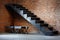 a minimalist metal staircase against a brick wall