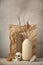 Minimalist monochrome still life composition with ceramic vase, cardboard podium, crumpled paper, natural stone