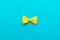 Minimalist photo of yellow bow tie on turquoise blue background and copy space