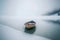 Minimalist picture of a small boat on a partially frozen lake. Winter landscape.