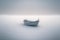 Minimalist picture of a small boat on a partially frozen lake. Winter landscape.