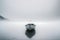 Minimalist picture of a small boat on a partially frozen lake. Winter landscape.