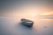 Minimalist picture of a small boat on a partially frozen lake. Winter landscape with sunset.