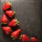 Minimalist presentation of strawberries on textured slate surface