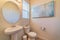 Minimalist small bathroom interior with toilet pedestal sink and round mirror