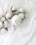 Minimalist spa composition. Bath bomb with cotton flowers on silk fabric background. Luxury beauty concept.