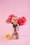 Minimalist still life with single gentle pink rose in a vase against a color background.