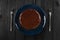 Minimalist style chocolate cake on dark blue plate on black table