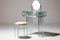 a minimalist vanity table with a round mirror, clear makeup organizer, and stool