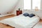 Minimalist white bed mattress on solid hardwood oak floor in cozy modern home bedroom.