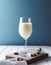 Minimalist wine glass full of milk against a blue background.