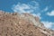 Minimalistic atmospheric landscape with rocky mountain wall with pointy top in sunny light. Loose stone mountain slope in the