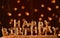 Minimalistic background with golden candles without fire letters in cake close up. Garland of yellow bokeh circles at