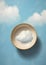 Minimalistic collage of blue sky with clouds inside a white bowl. Collage-style painting. Top view