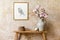 Minimalistic composition of living room interior with gold mock up frame, wooden bench, gold clock, magnolia in vase.