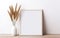 Minimalistic design. Mock up poster frame, vase with dry pampas grass in vase on wooden shelf and white wall background. Natural